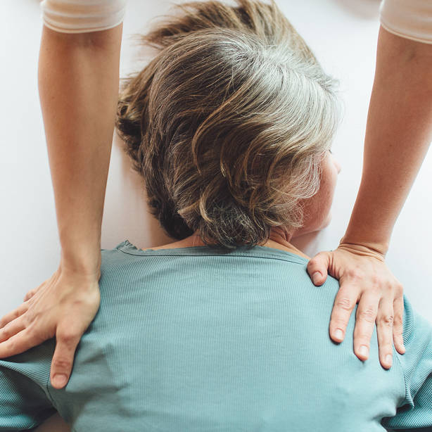 Shiatsu Behandlung - Hände am Rücken am Schulterblatt