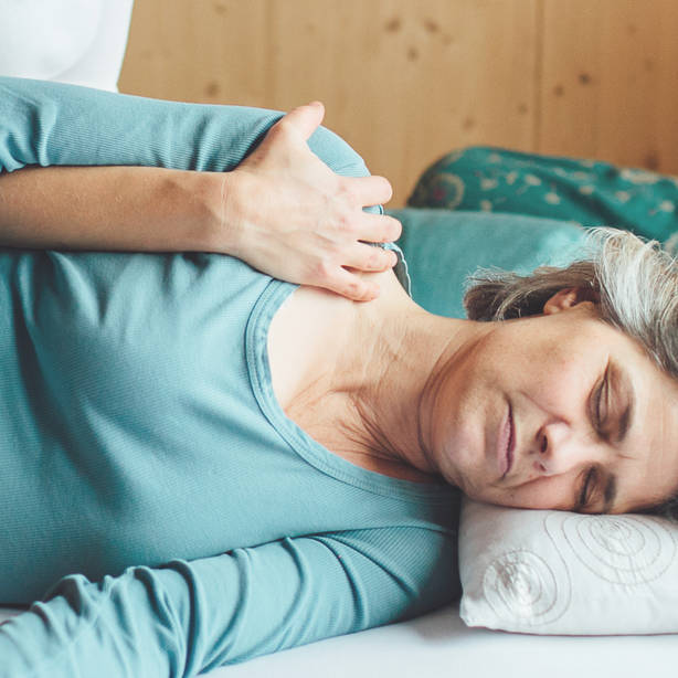 Shiatsu Behandlung bei einer auf der Seite liegenden Person an der Schulter