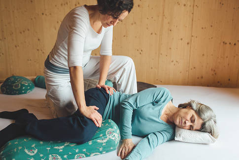Shiatsu Behandlung am Becken und Oberschenkel bei einer auf der Seite liegenden Person