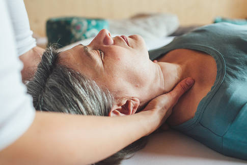 Shiatsu Behandlung im Nacken bei einer am Rücken liegenden Person